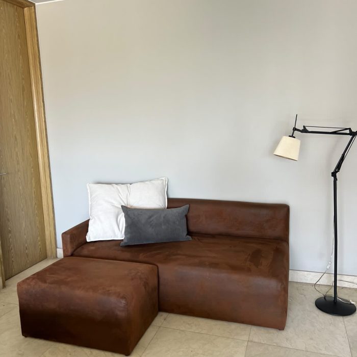 Sofa tapizado en tela simil cuero, va con 2 cojines.